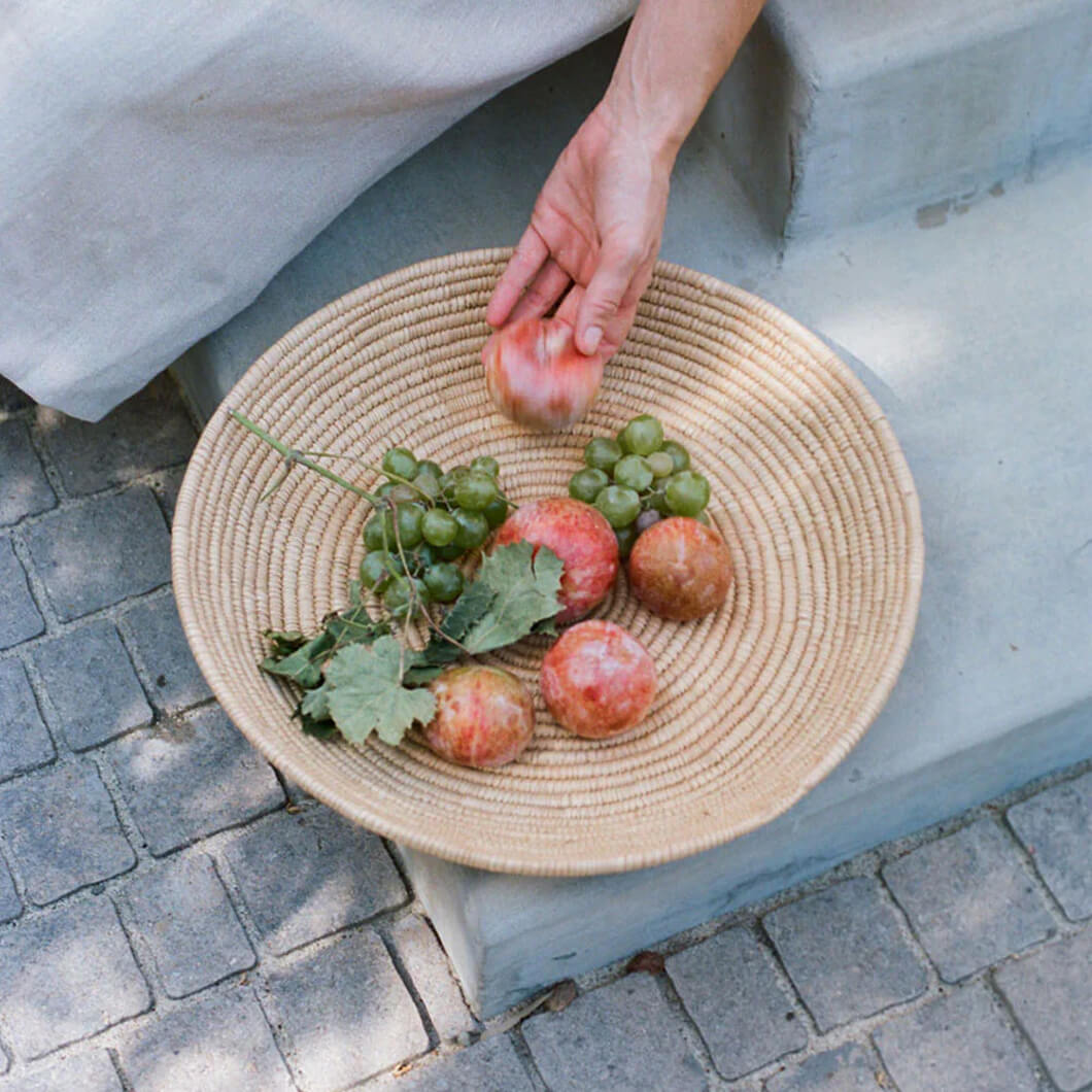 Palm leaf basket with fresh fruit on a linen-draped table