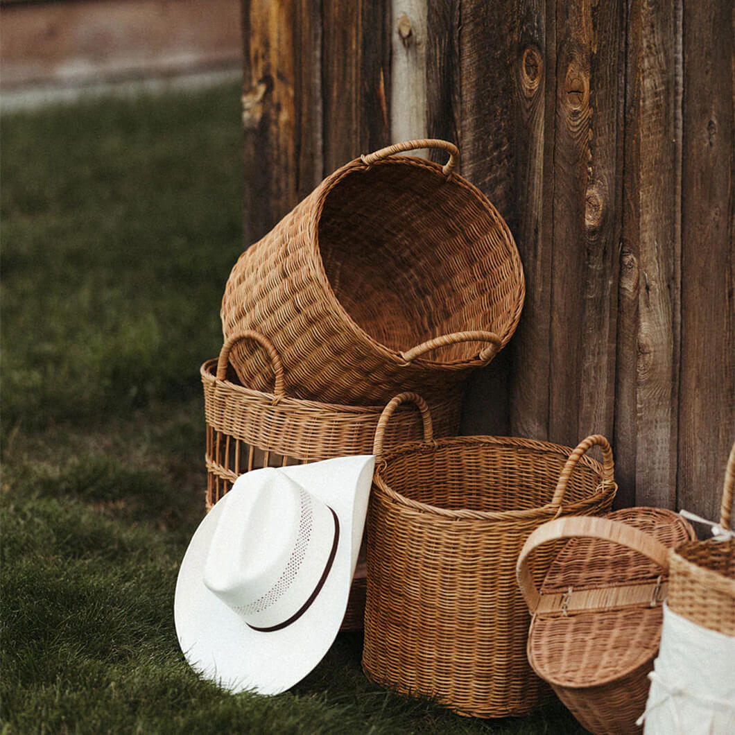 Stacked rattan baskets with a straw hat against a wooden wall