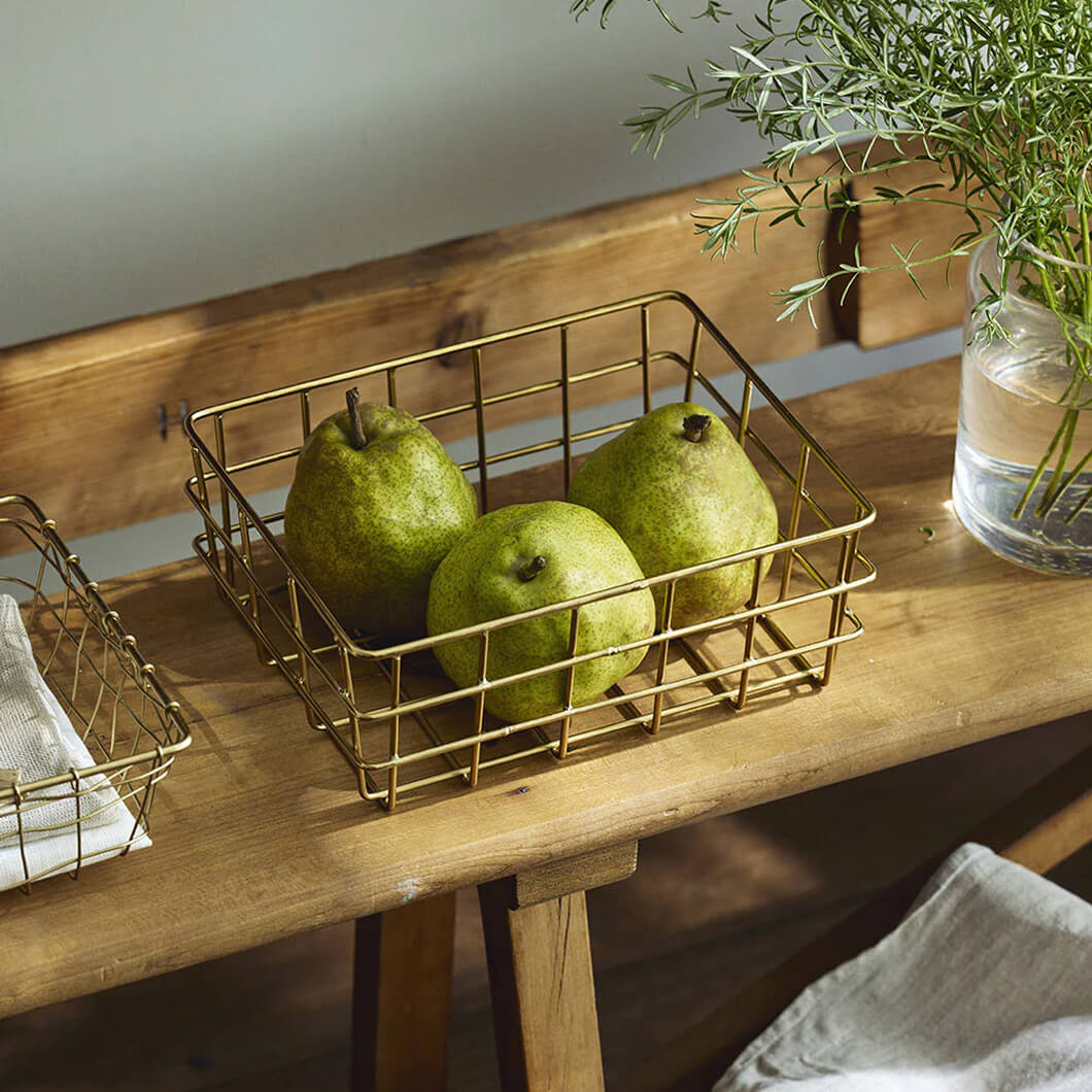 Hand-forged wire basket holding pears on a wooden table