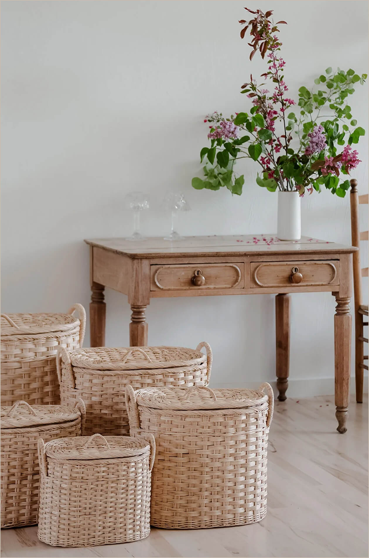 Handwoven rattan baskets beside a wooden table with fresh flowers