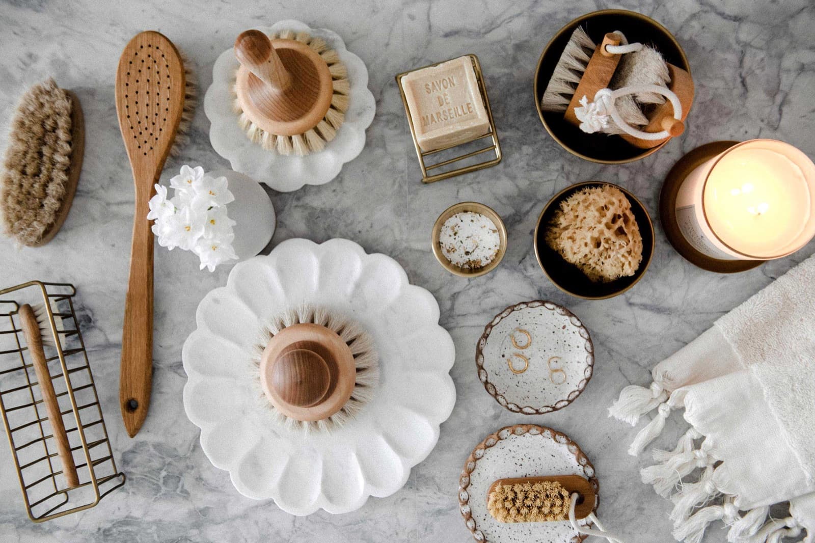 Bath brushes, a brass soap dish and ceramic trays laid out on grey marble
